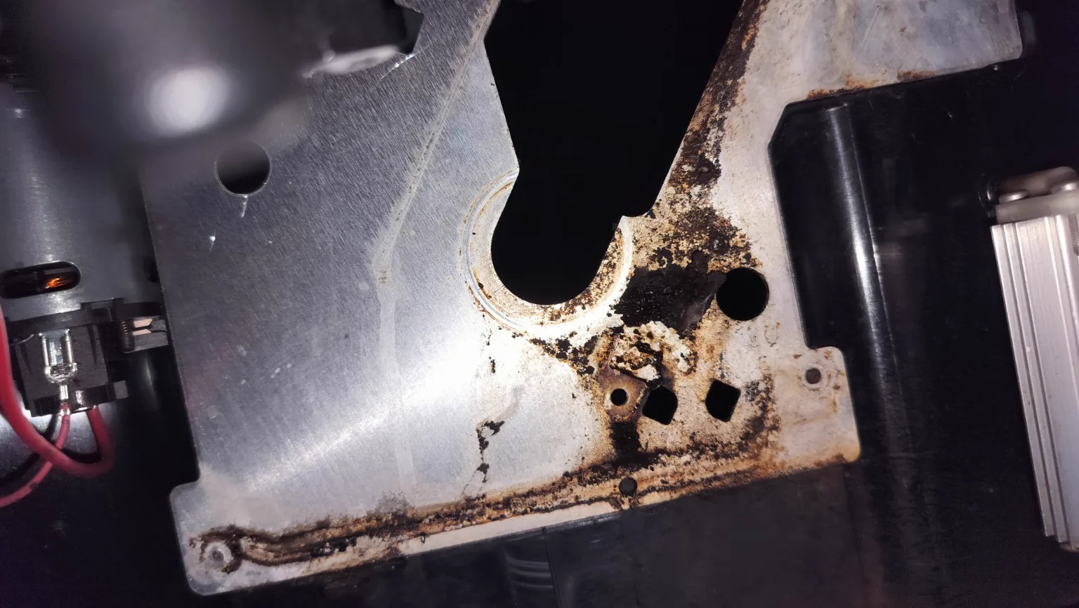 Internal drainage area of a Miele built-in coffee machine during workshop inspection, showing coffee residue and dried moisture traces.