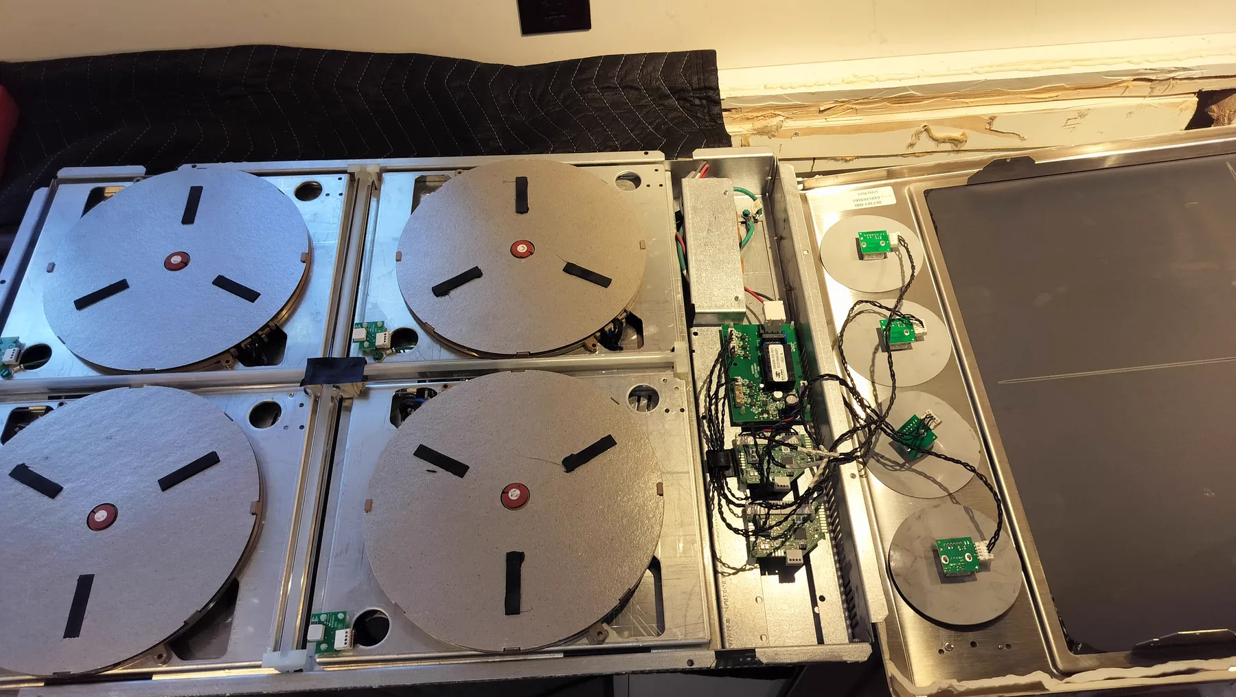 High-end induction cooktop opened to expose cooking modules and control electronics.