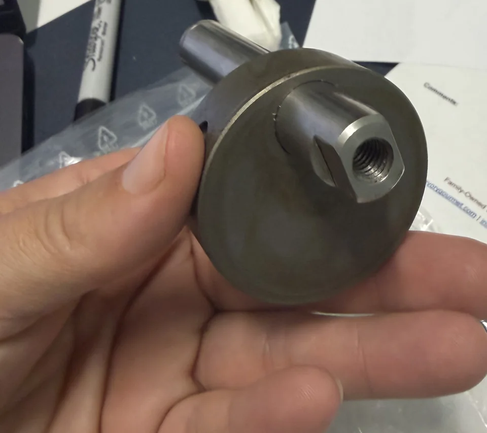 Close-up of a metal cam-like adjustment component held for identification