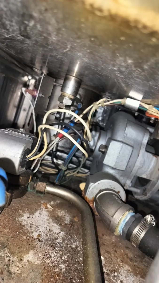Internal pump, drain hardware and hose connections inside a CMA commercial dishwasher during inspection.