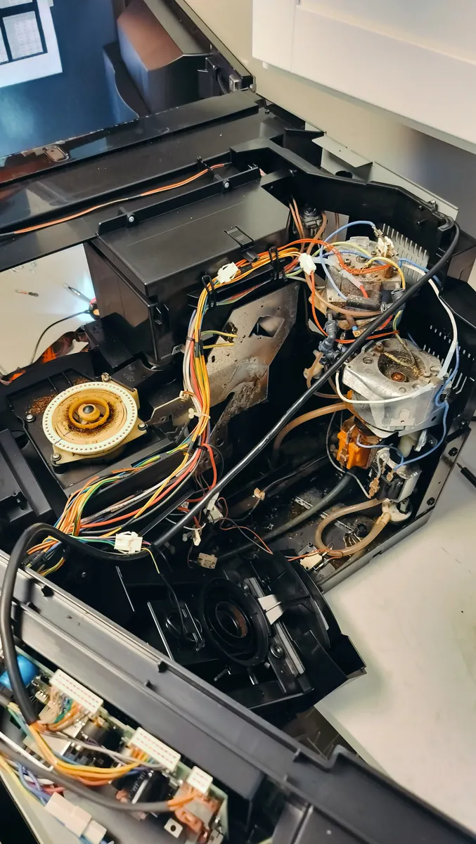 Miele coffee machine opened for inspection, showing internal tubing, wiring and residue around the assemblies.