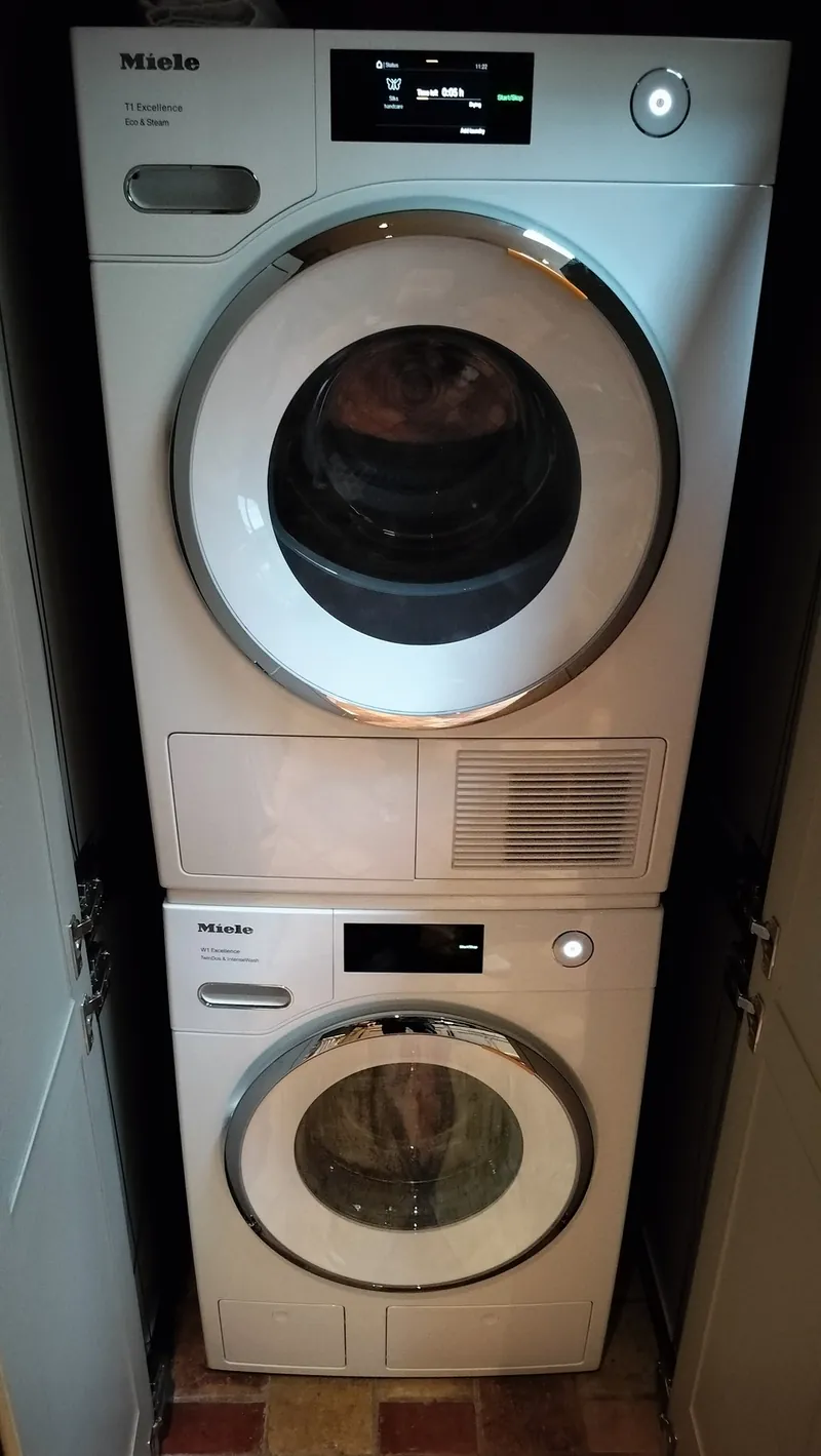 Stacked Miele washer and heat-pump dryer in a built-in laundry cabinet.