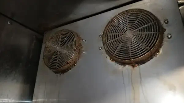 Walk-in cooler evaporator fan area with visible dirt and debris buildup documented by KONGRA